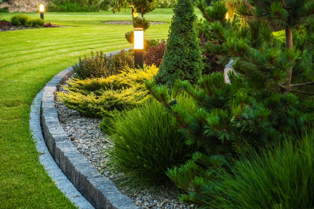 Concrete curbing vs landscape edging showing a continuous concrete border around residential planting beds